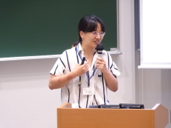 演台に立つストライプの服を着た女性