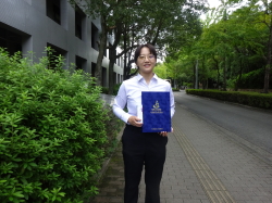 卒業証書を持って立つ女性