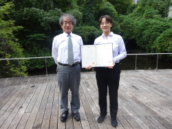 証書を広げて立つ女性と男性