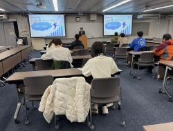 教室で説明を聞く学生たち