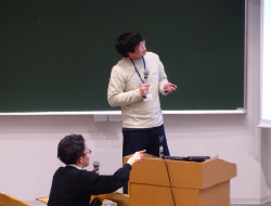 黒板の前で話す2人の男性